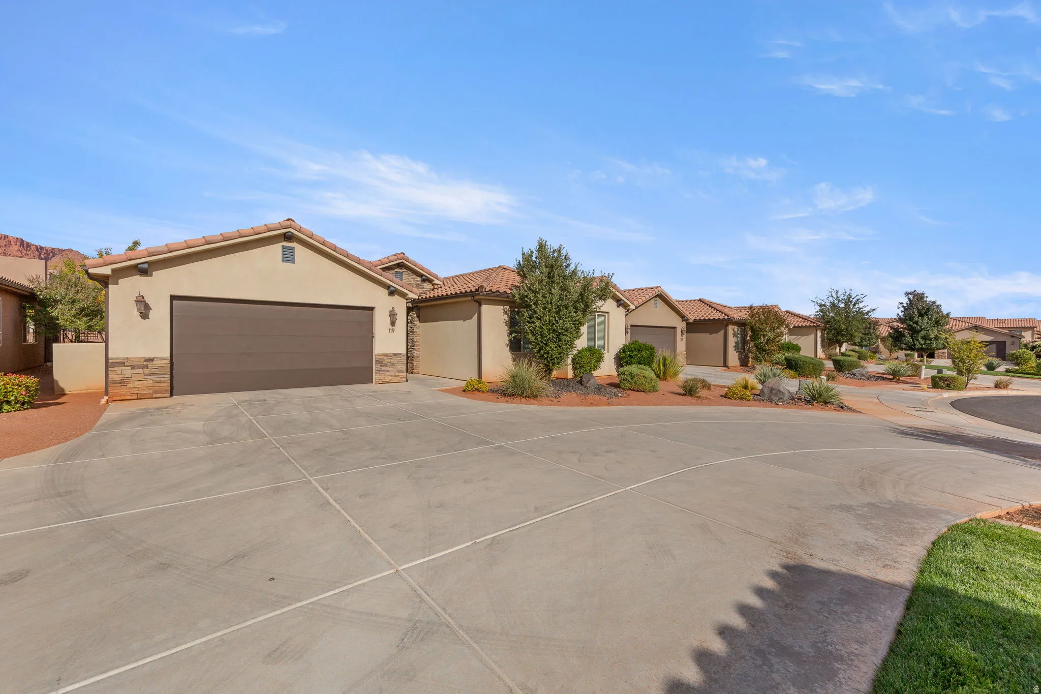 Mediterranean / spanish house featuring stone siding, stucco siding, concrete driveway, and a residential view