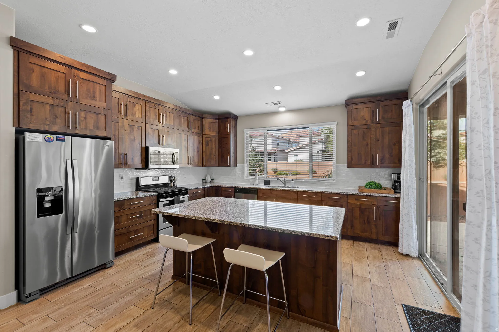 Kitchen featuring stainless steel appliances, recessed lighting, light stone counters, a kitchen island, and decorative backsplash