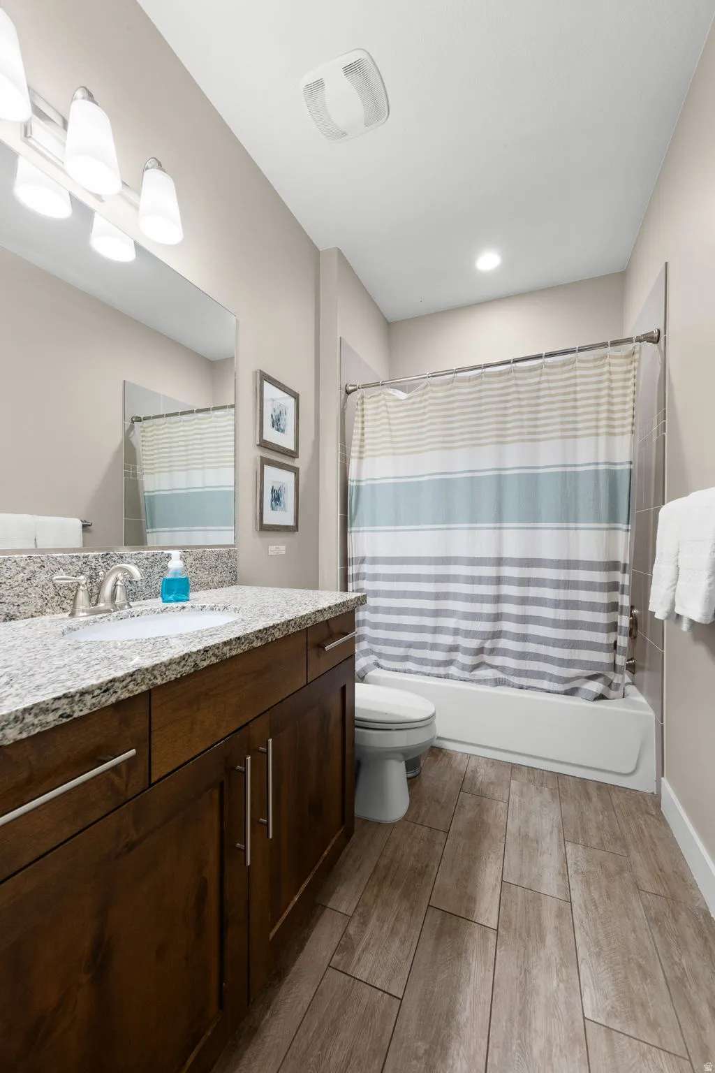 Full bathroom with vanity, shower / tub combo, and wood finish floors