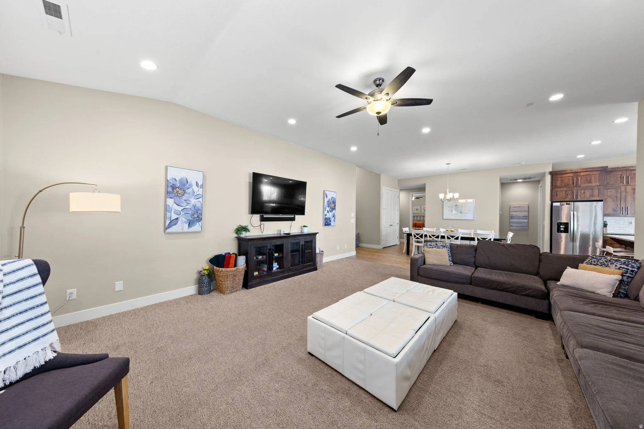 Living area featuring light carpet, recessed lighting, ceiling fan, vaulted ceiling, and a chandelier