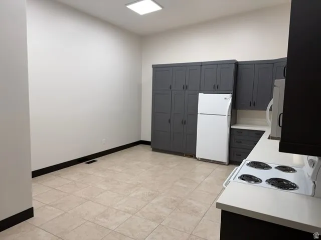 Kitchen with light countertops, white appliances, and gray cabinetry
