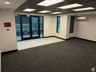 Spare room featuring carpet, a drop ceiling, and a wall mounted air conditioner
