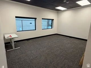 Empty room with dark colored carpet and a paneled ceiling