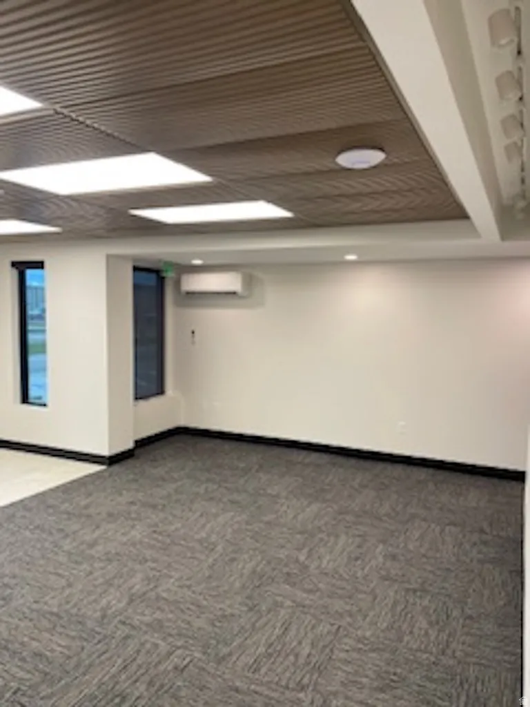 Empty room featuring carpet flooring and an AC wall unit