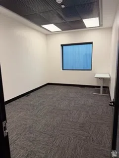 Unfurnished room with dark carpet and baseboards