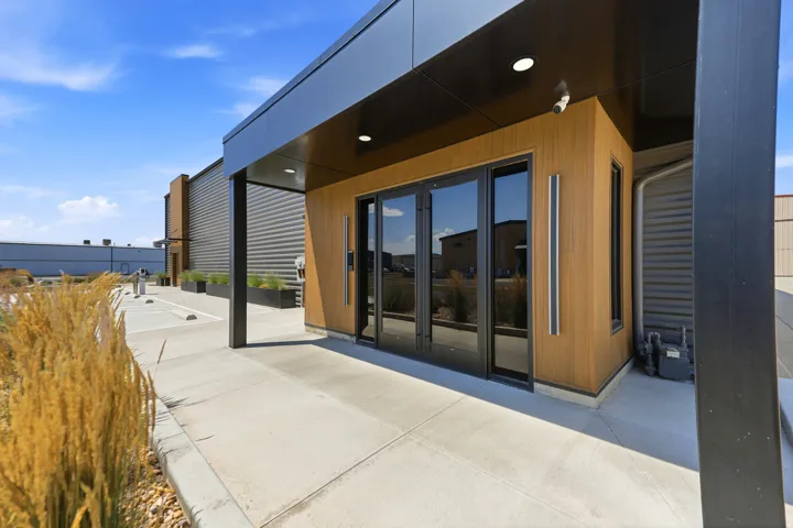 Modern commercial building entrance featuring wood-look paneling and black-framed glass doors