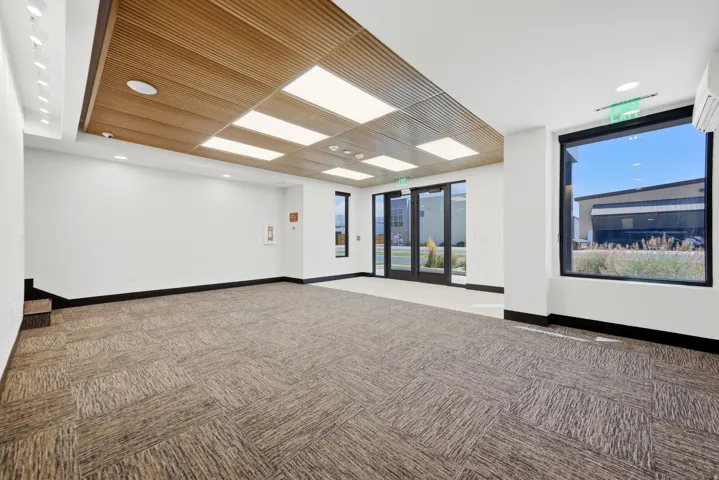 Spacious open-concept interior featuring textured carpet flooring and a wood-slat ceiling with recessed lighting