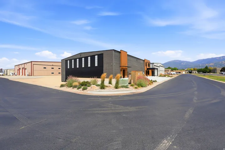 Modern commercial building featuring dark paneling, vertical windows, and a contrasting orange architectural accent