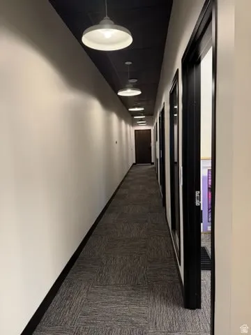 Hallway with dark carpet and baseboards