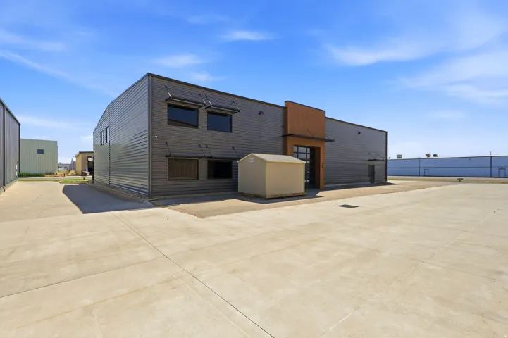 Industrial building featuring corrugated metal siding and a large concrete lot