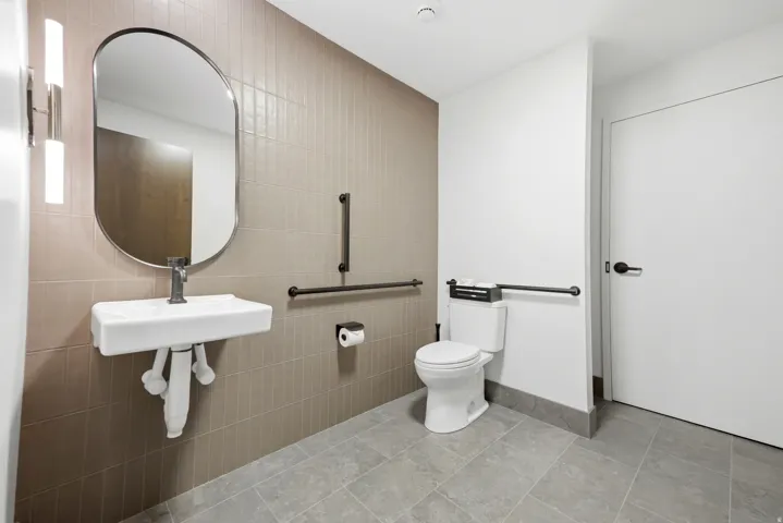 Modern bathroom featuring a rectangular wall-mounted sink with a dark-finish faucet, an arched mirror, and dual vertical wall sconces