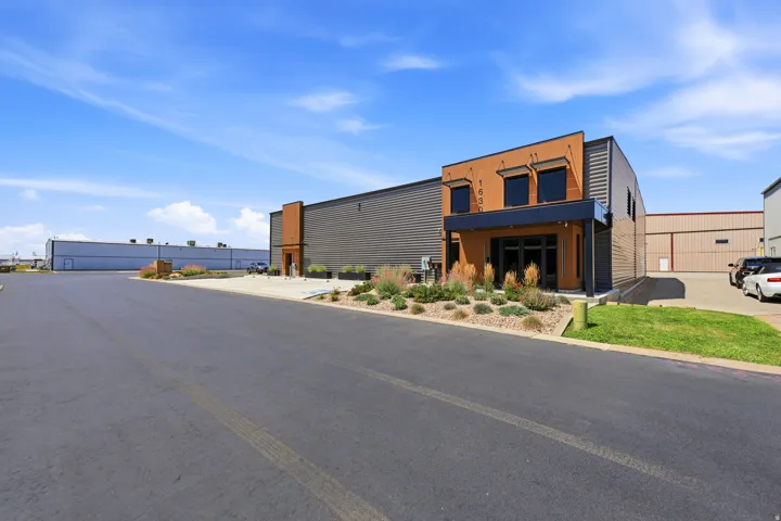 Contemporary commercial building featuring a two-story entrance with expansive windows, a contrasting dark metal façade, and a tan stucco accent wall
