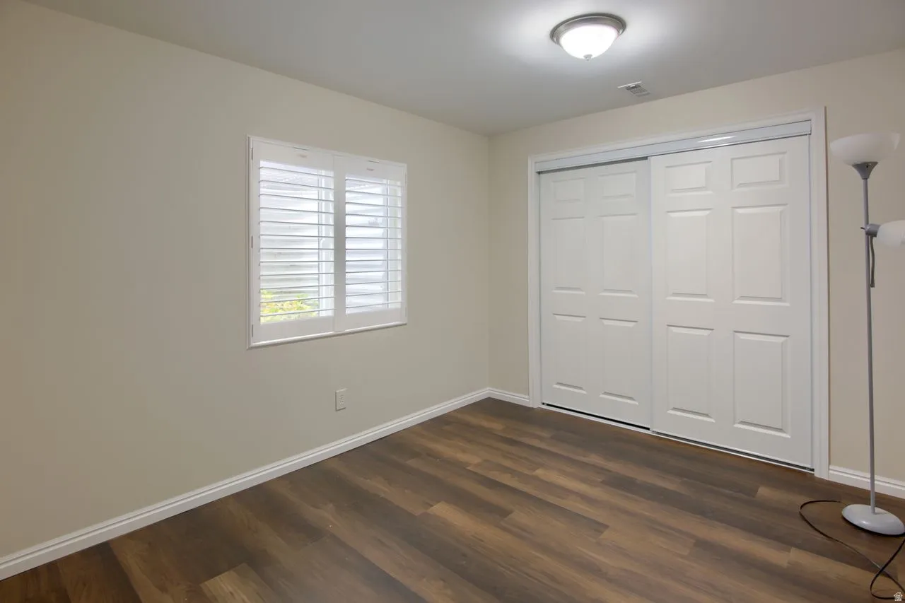Unfurnished bedroom featuring dark wood-type flooring and a closet