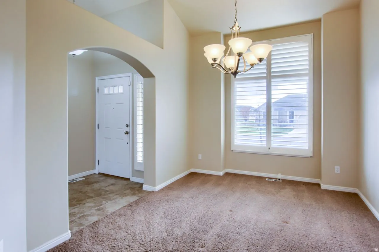 Entryway with arched walkways, light colored carpet, and a chandelier