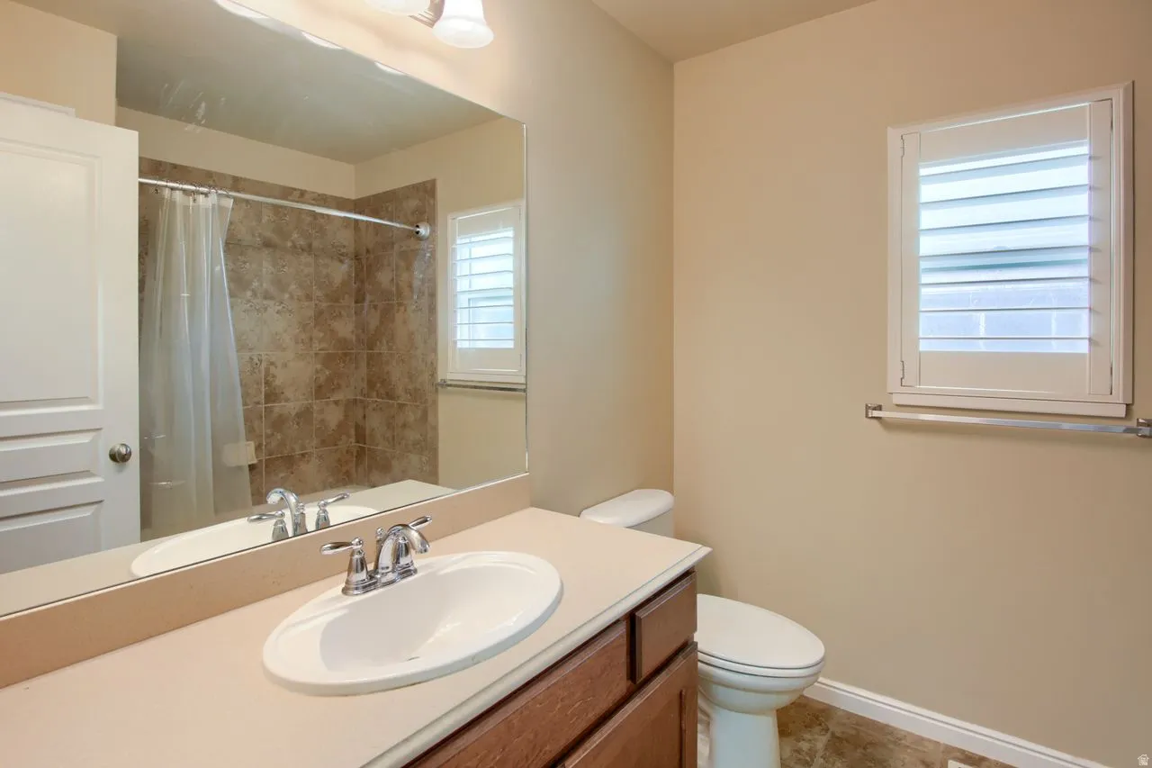 Full bathroom featuring a shower with shower curtain, vanity, and light tile patterned flooring