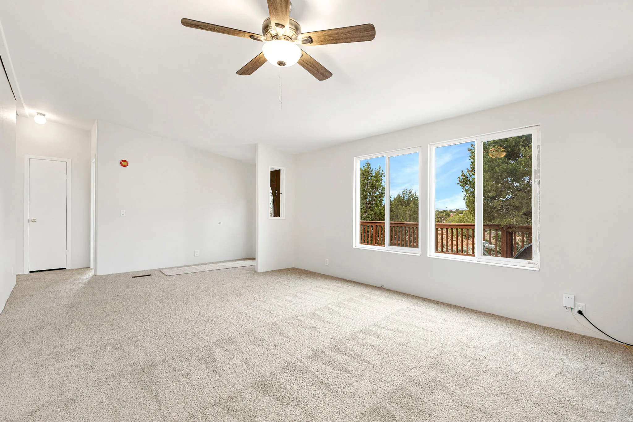 Spare room featuring a ceiling fan, light colored carpet, and attic access