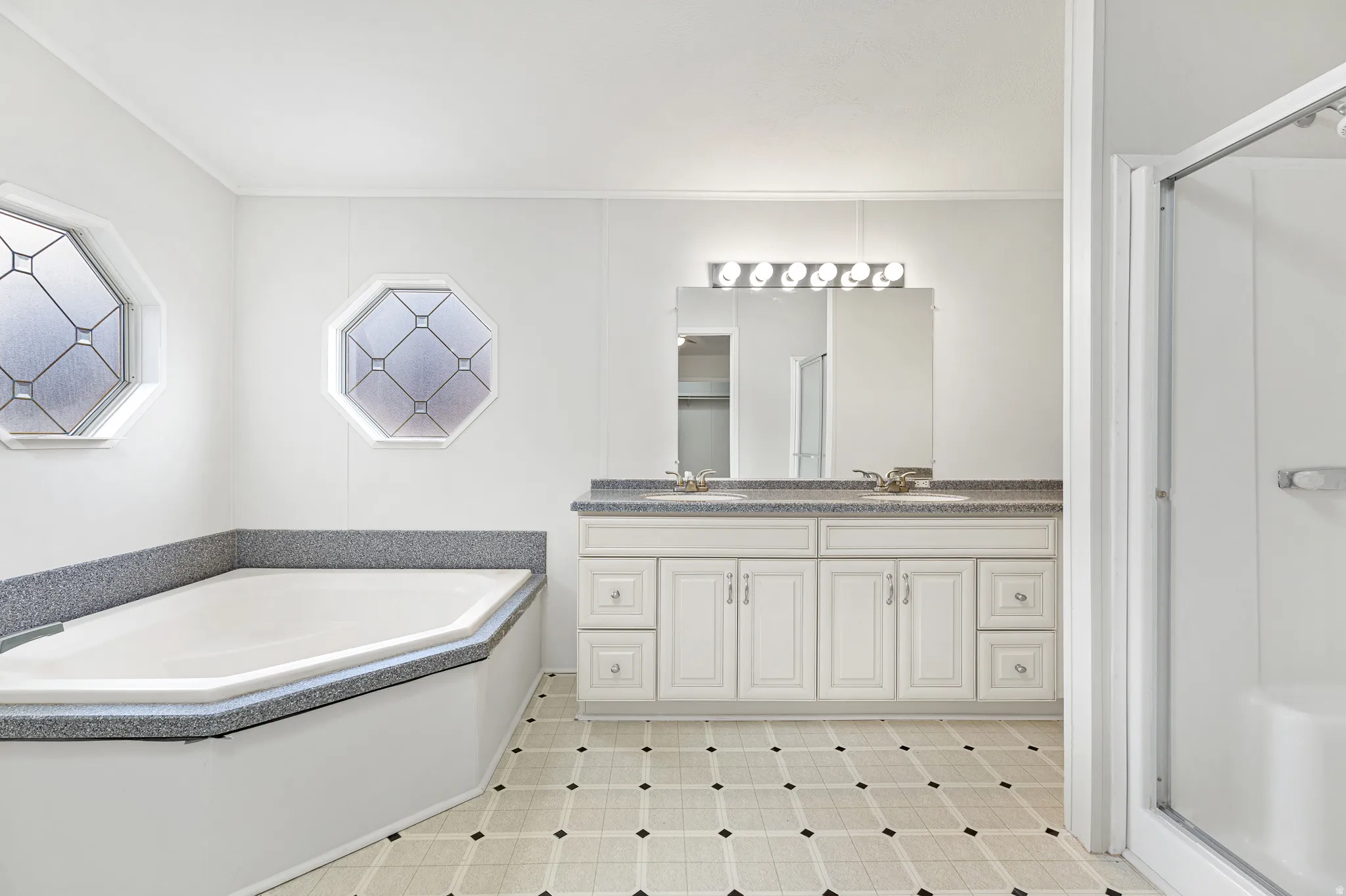Bathroom featuring a shower stall, double vanity, and a garden tub