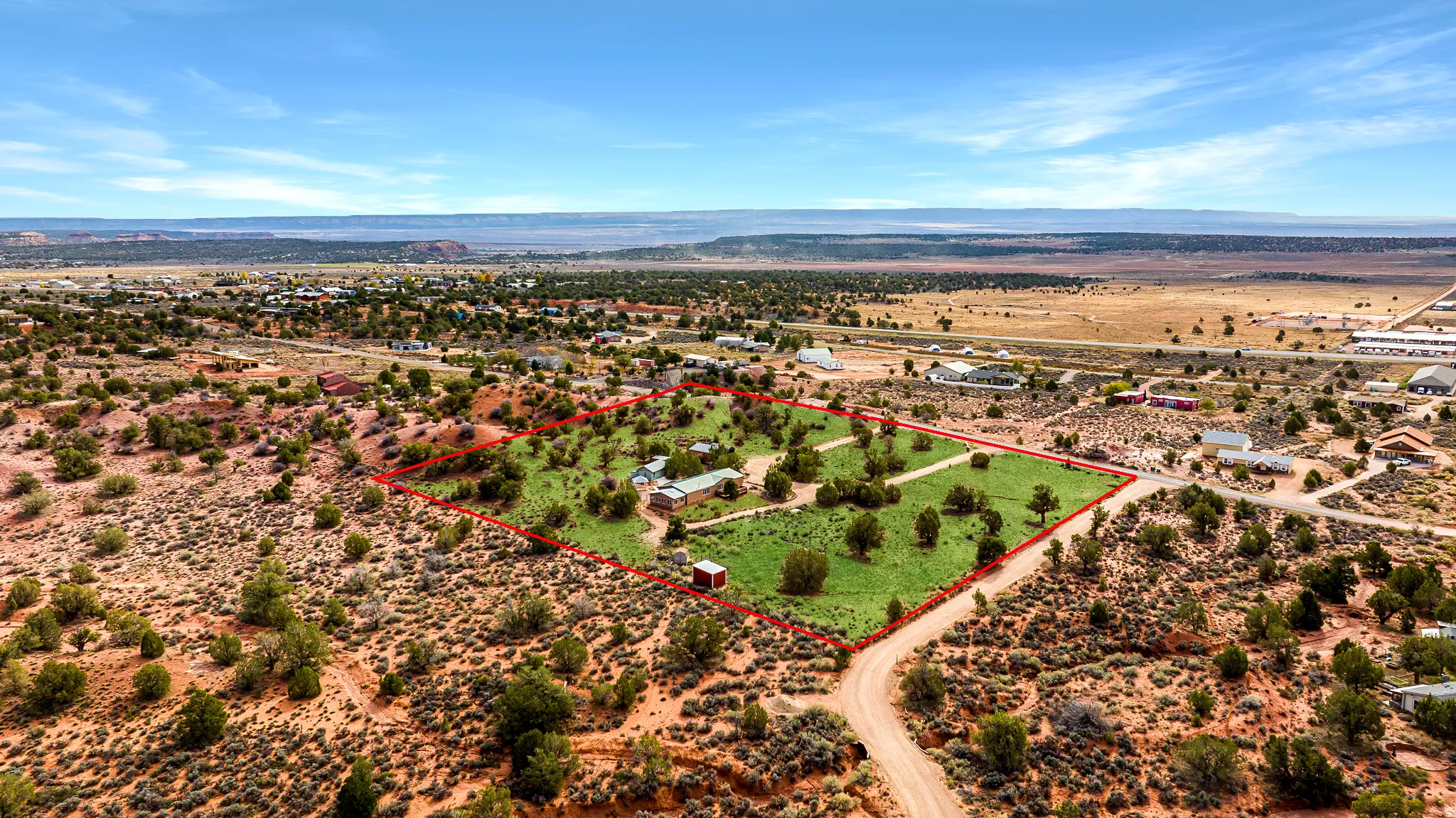 Aerial view of sparsely populated area featuring property boundaries highlighted and a mountainous background