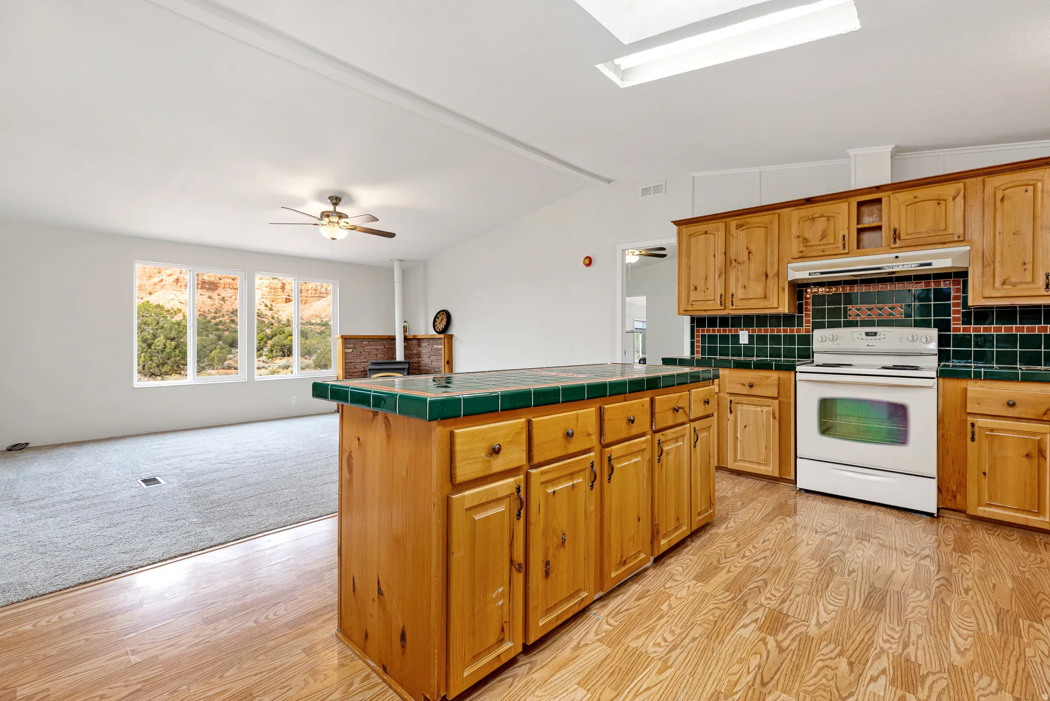 Kitchen featuring decorative backsplash, white range with electric cooktop, tile countertops, a ceiling fan, and open floor plan