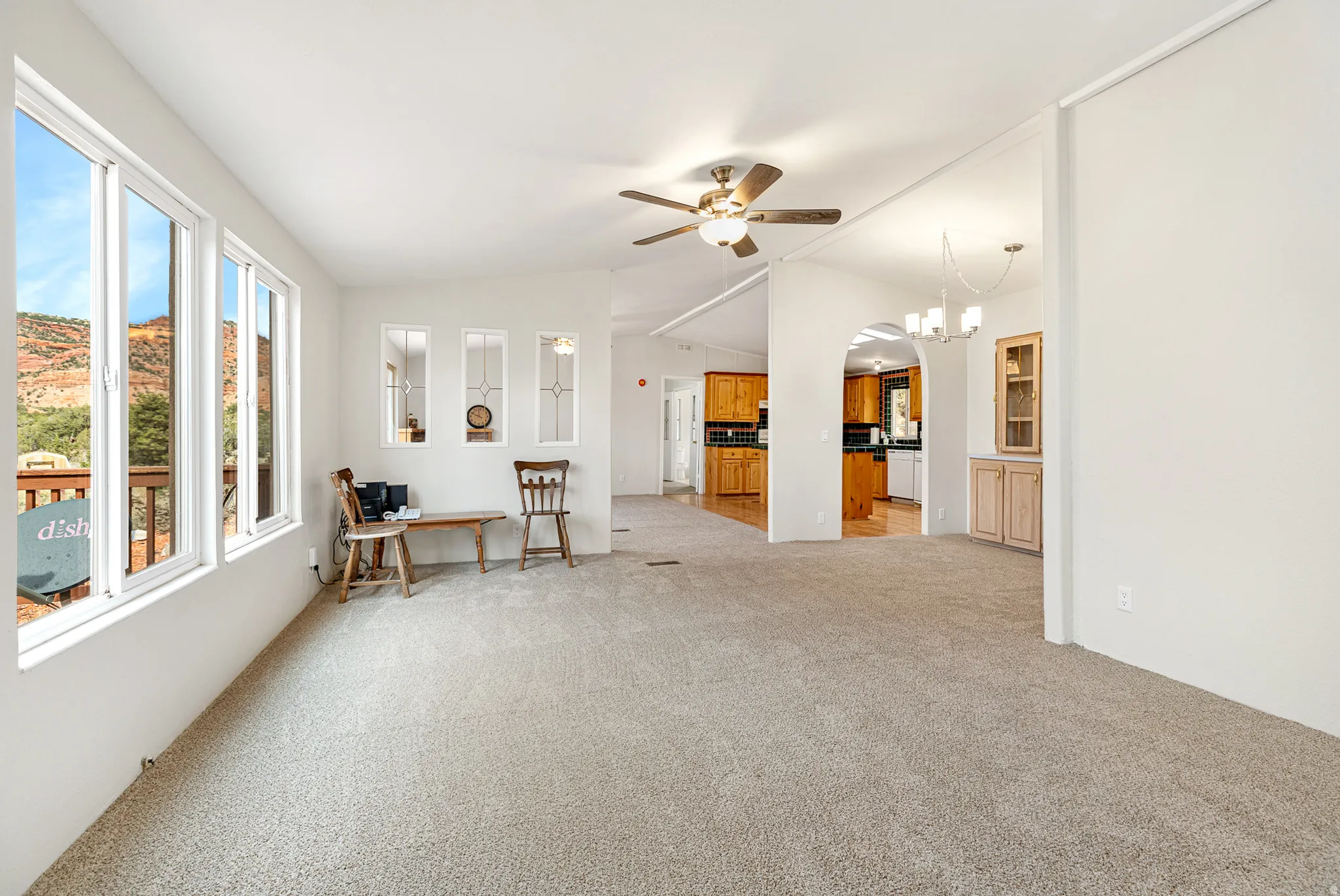 Living room with vaulted ceiling, a chandelier, light carpet, and ceiling fan