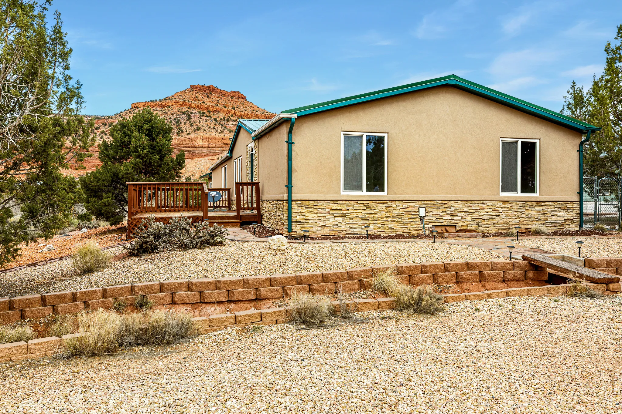 View of side of home with stone siding, a wooden deck, and stucco siding