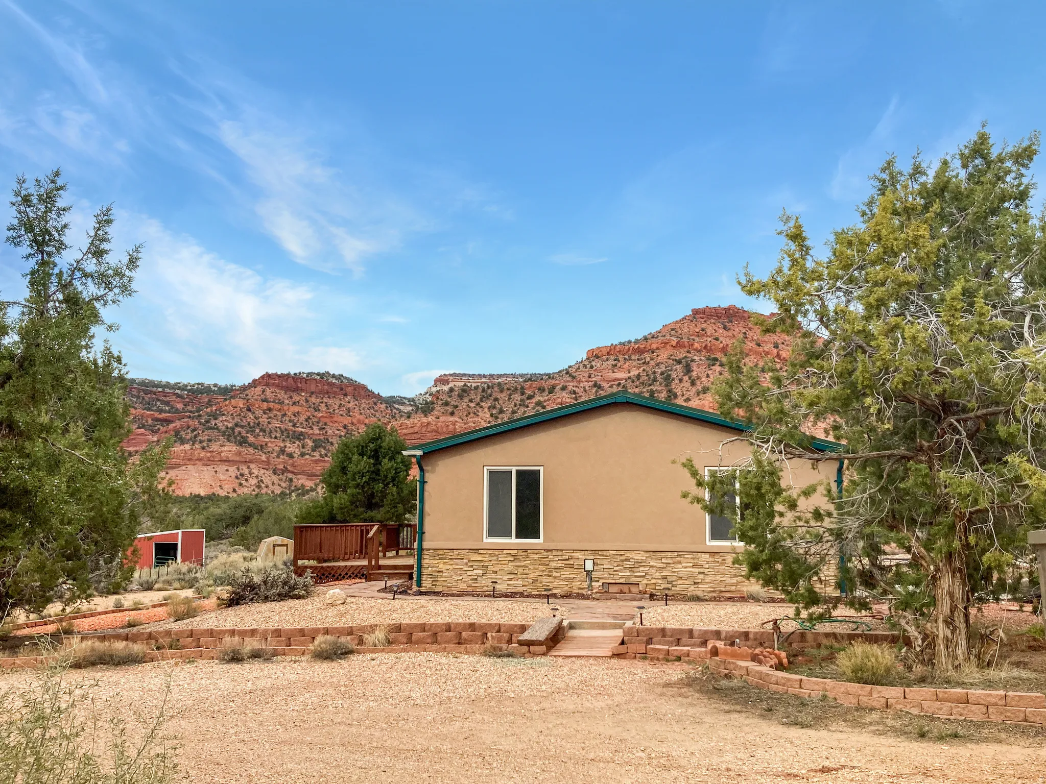 View of property exterior with stucco siding, stone siding, and a deck with mountain view