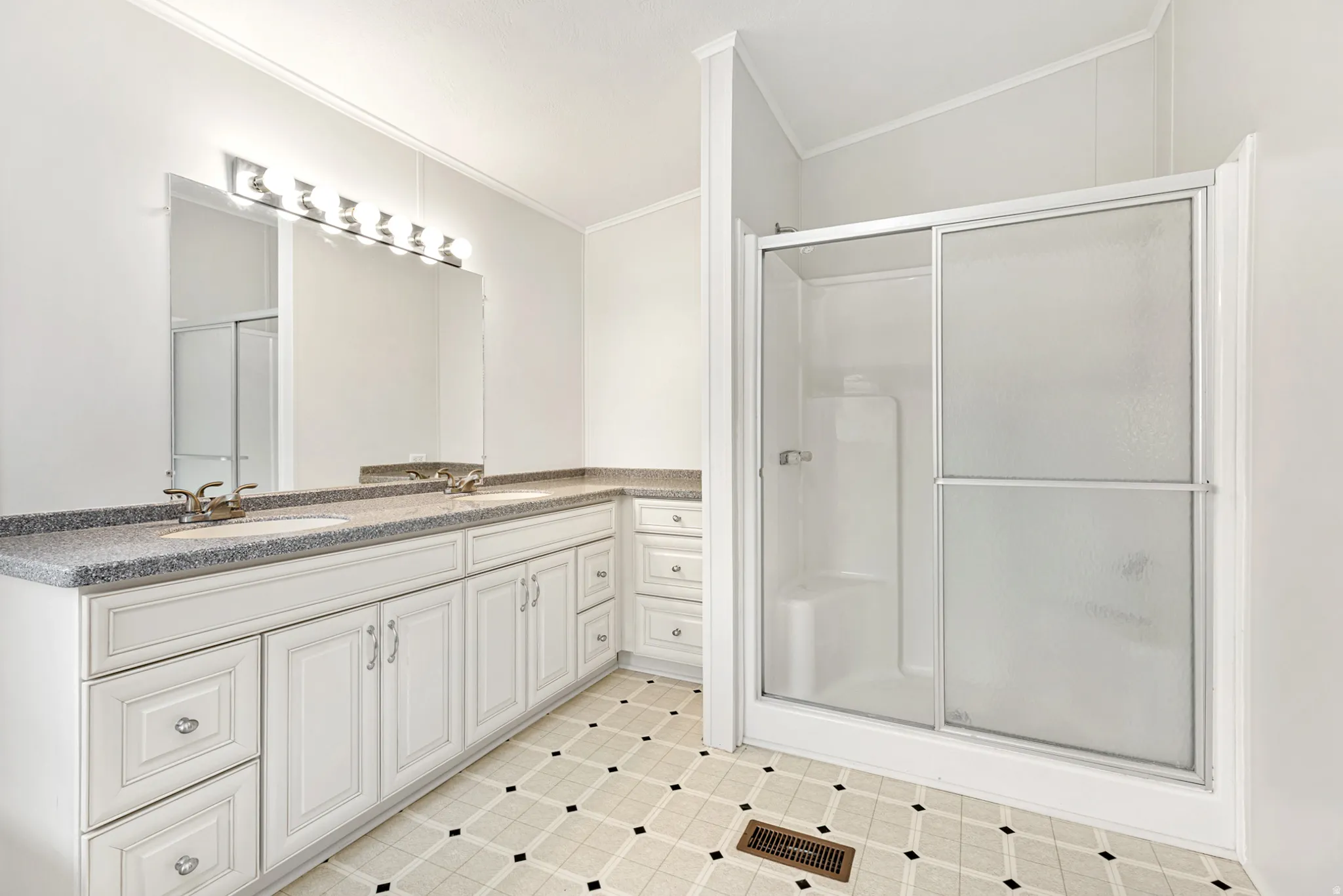 Bathroom with double vanity, a stall shower, ornamental molding, and light tile patterned flooring