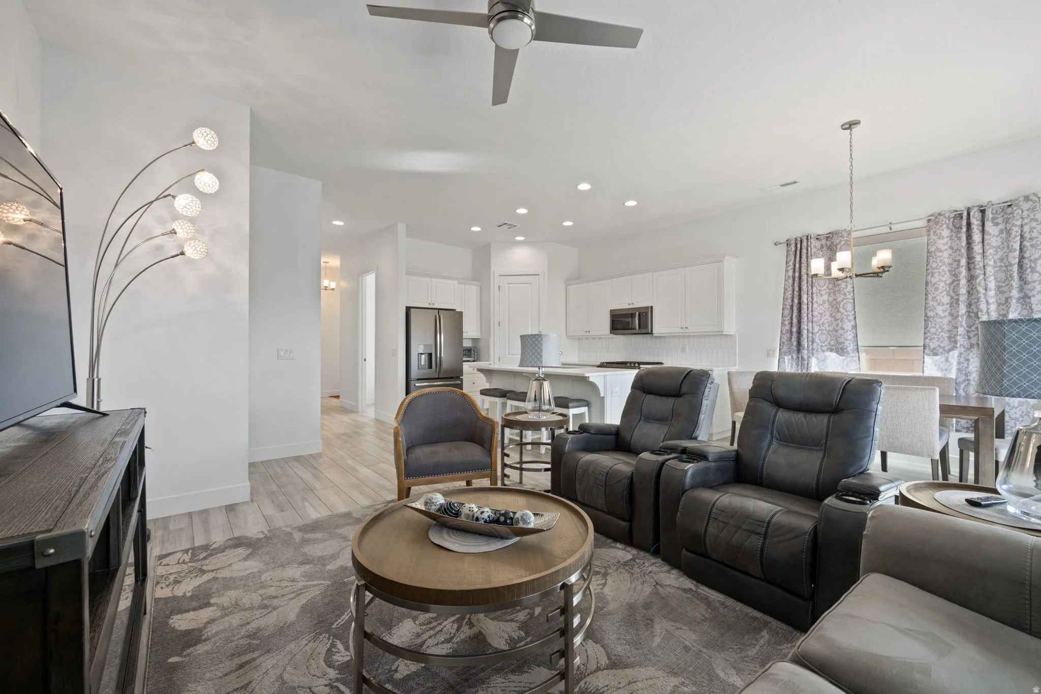 Living room with a chandelier, light wood-style floors, recessed lighting, and ceiling fan