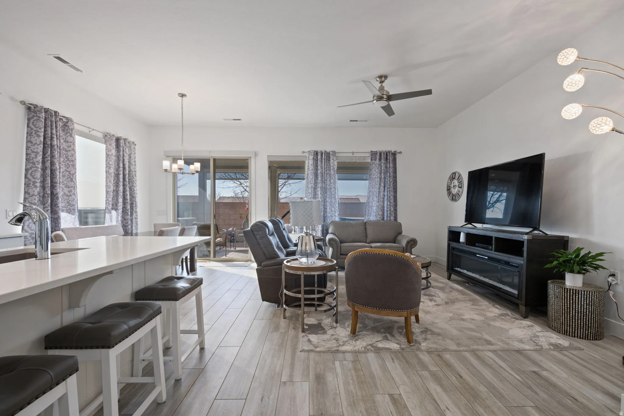 Living area with a chandelier, light wood-type flooring, and ceiling fan