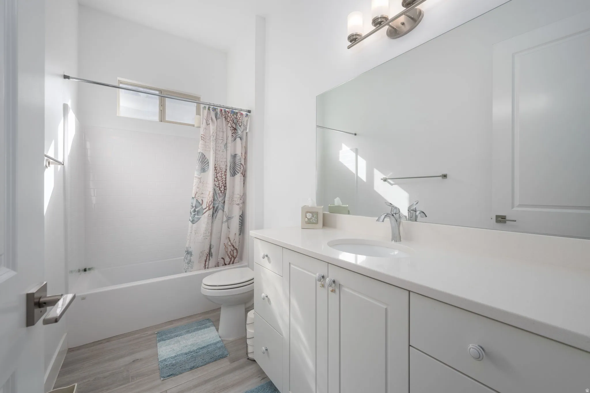 Full bathroom with shower / tub combo, vanity, and light wood-type flooring