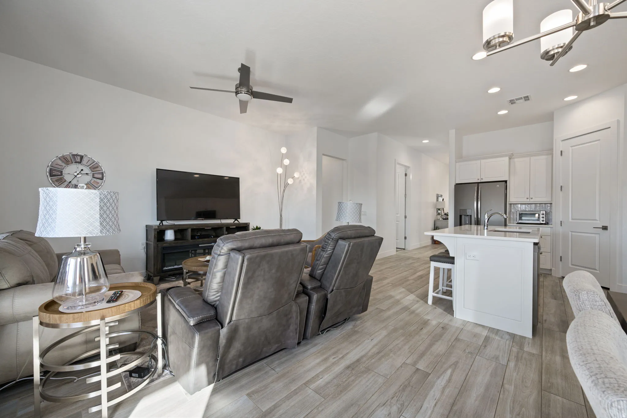 Living room with recessed lighting, light wood-style flooring, a ceiling fan, and a chandelier