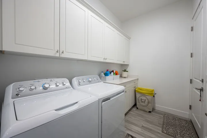 Laundry room featuring light wood-type flooring, cabinet space, and washing machine and clothes dryer
