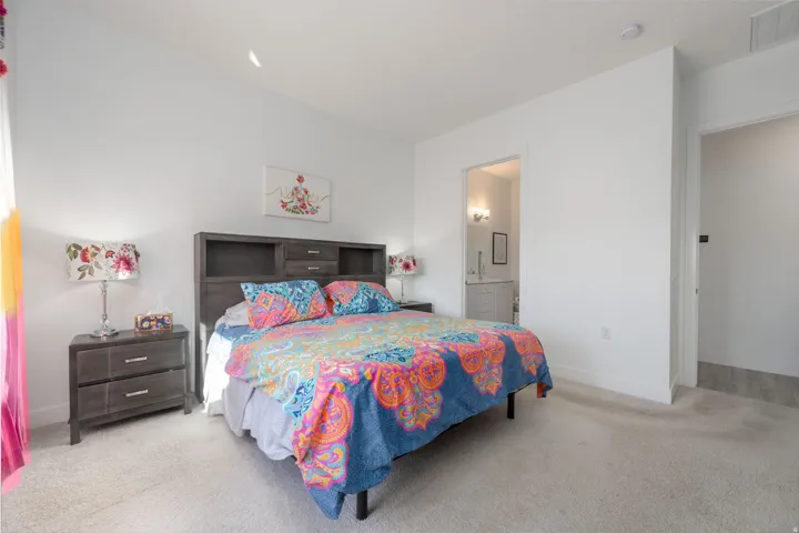Carpeted bedroom featuring baseboards and ensuite bathroom