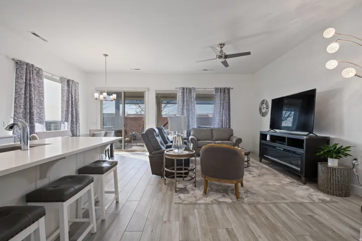 Living area with a chandelier, light wood-type flooring, and ceiling fan