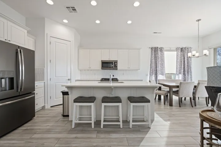 Kitchen featuring stainless steel appliances, a kitchen island with sink, recessed lighting, backsplash, and a breakfast bar area