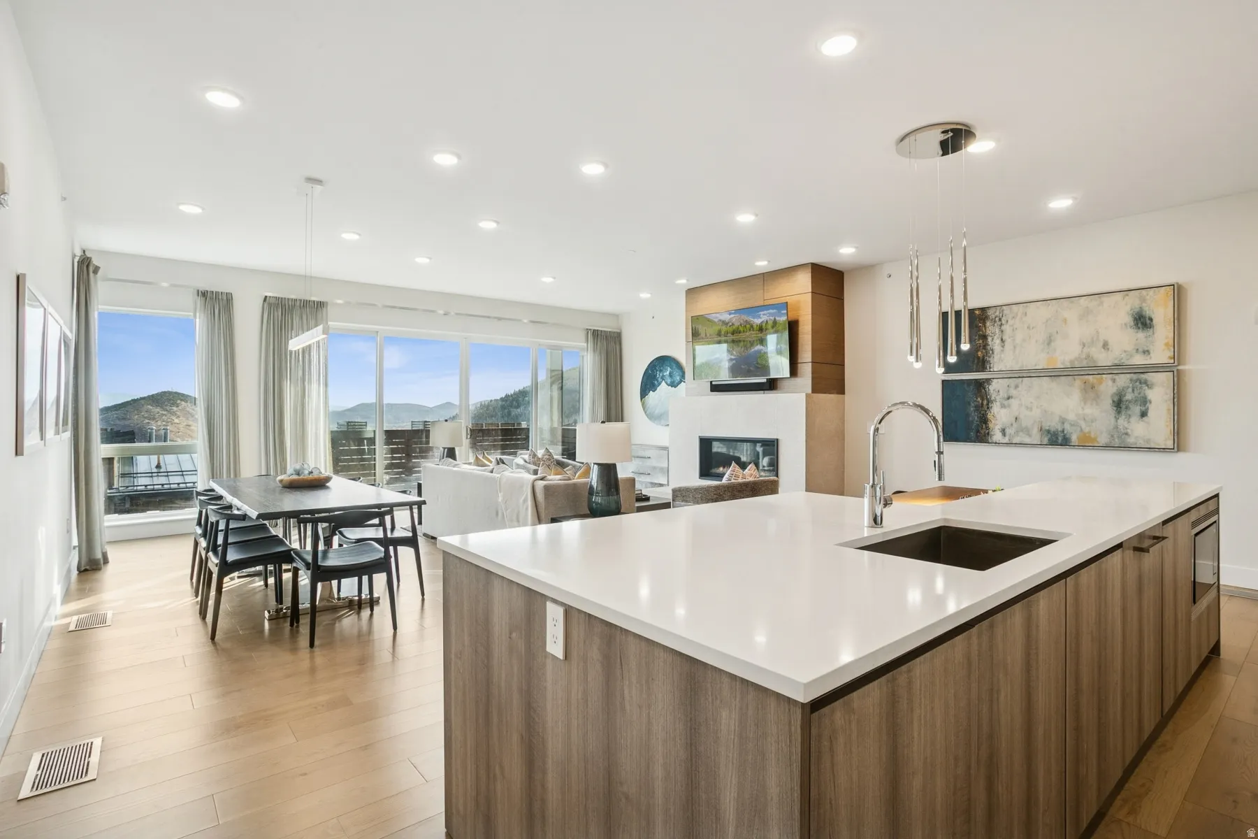 Kitchen with modern cabinets, brown cabinetry, a fireplace, a large island, and pendant lighting
