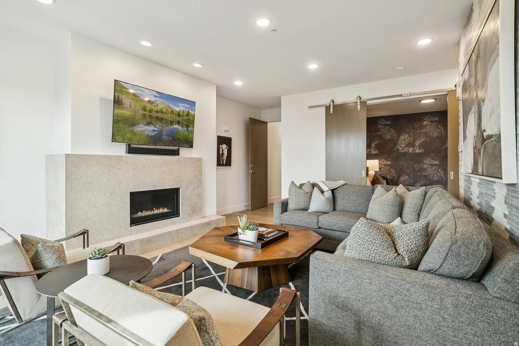 Living room with a barn door, recessed lighting, a premium fireplace, and wood finished floors