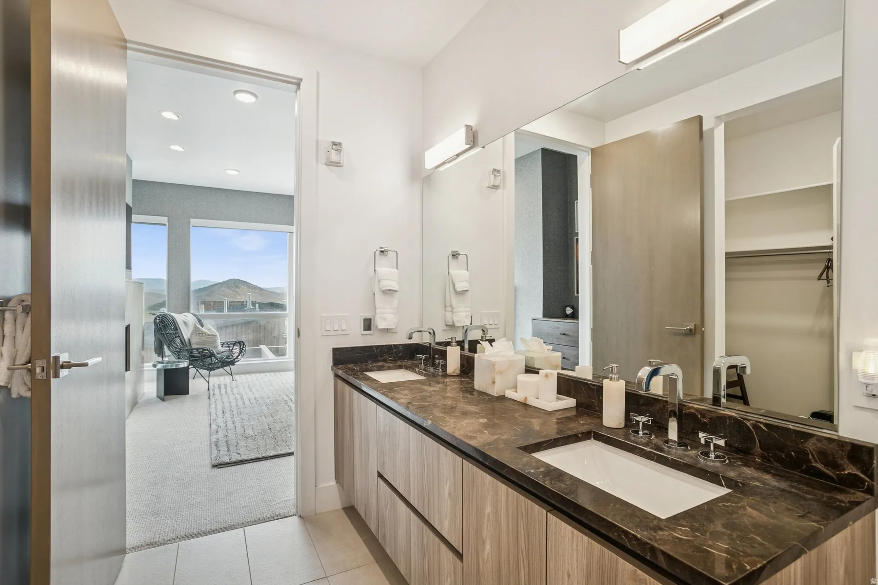 Full bath featuring light colored carpet, light tile patterned flooring, double vanity, recessed lighting, and a spacious closet