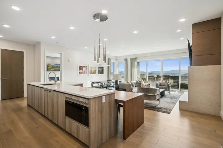 Kitchen with modern cabinets, light wood-style floors, decorative light fixtures, stainless steel microwave, and recessed lighting