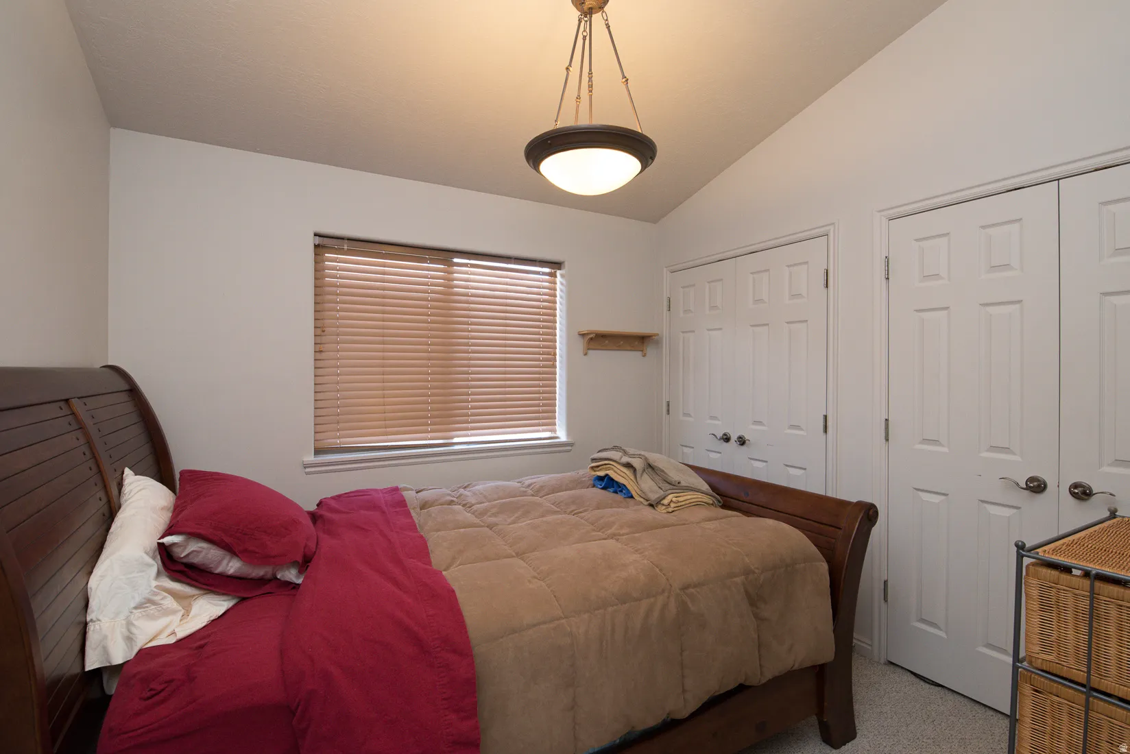 Bedroom featuring multiple closets, carpet, and vaulted ceiling