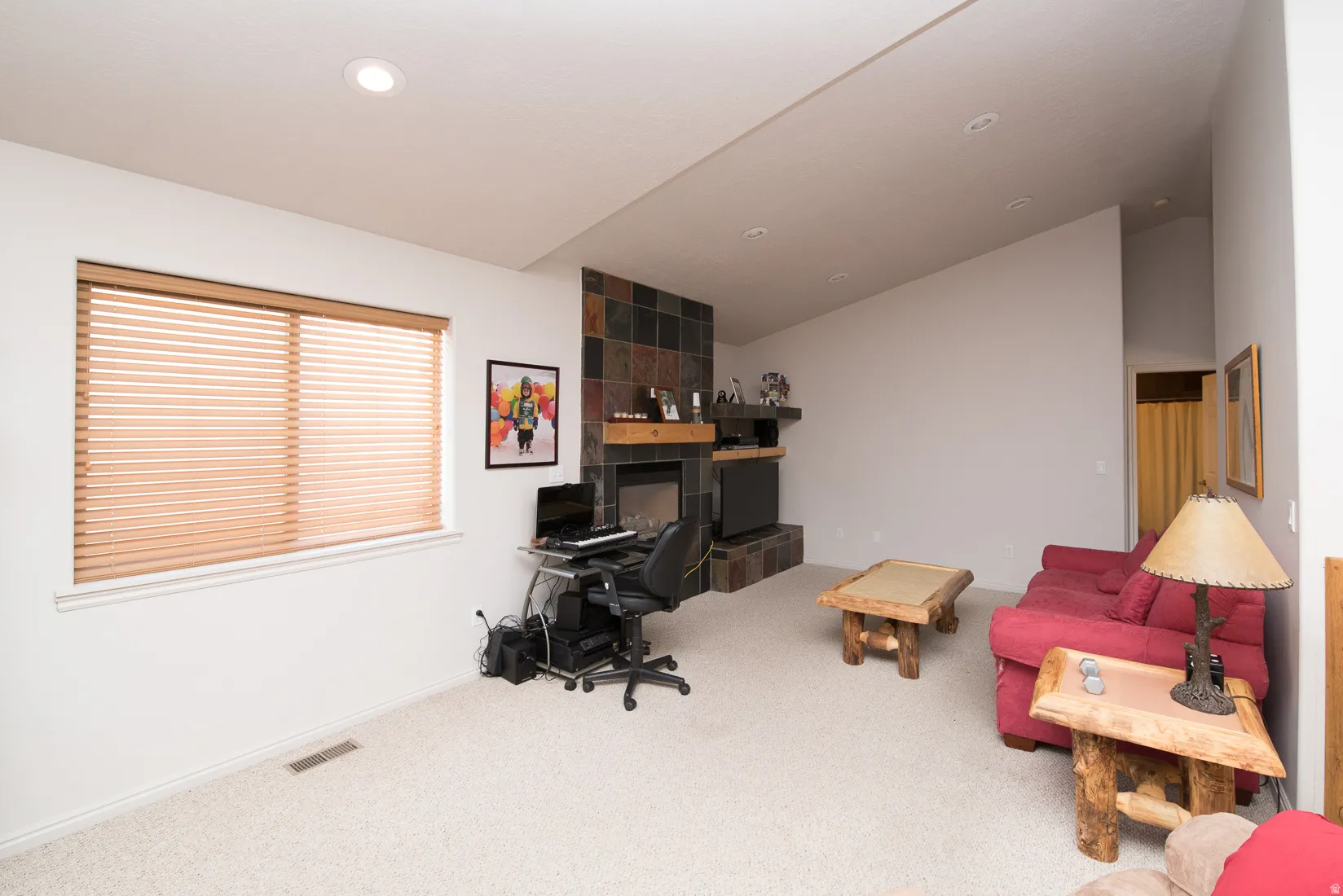 Carpeted home office with lofted ceiling and baseboards