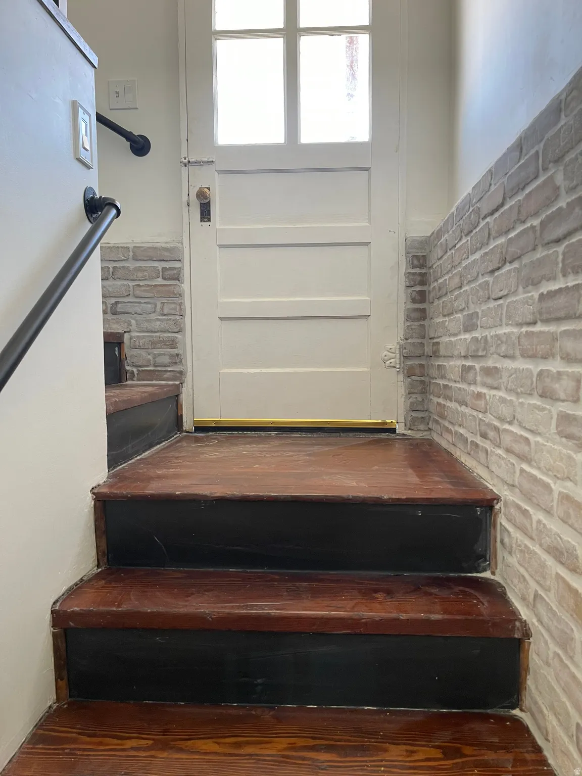 Stairs featuring brick wall and wood finished floors