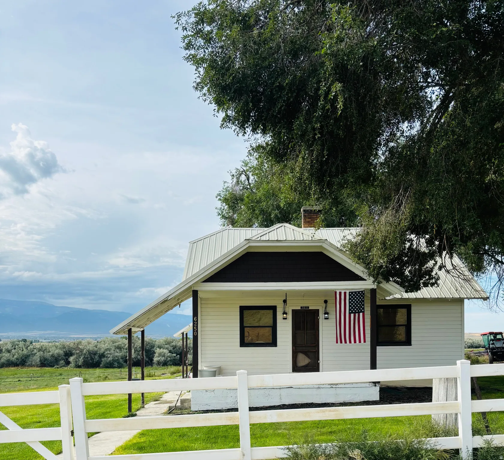 View of front of house with a porch, a fenced front yard, a metal roof, and a chimney