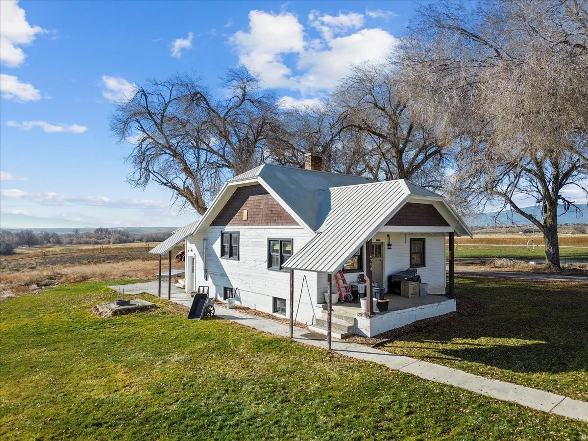 View of home's exterior with covered porch, a metal roof, a yard, and a chimney