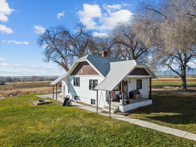 View of home's exterior with covered porch, a metal roof, a yard, and a chimney