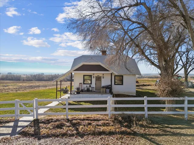 Bungalow featuring a porch, a view of rural / pastoral area, a fenced front yard, and a chimney