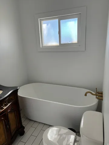 Full bathroom featuring a freestanding bath, vanity, and light tile patterned floors