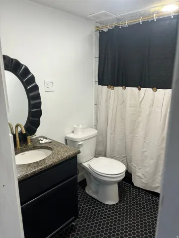 Bathroom with a shower with shower curtain, vanity, and dark tile patterned flooring