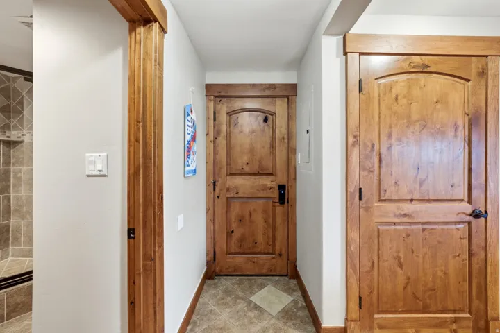 Hallway featuring wood-finish doors with arched panels and dark hardware