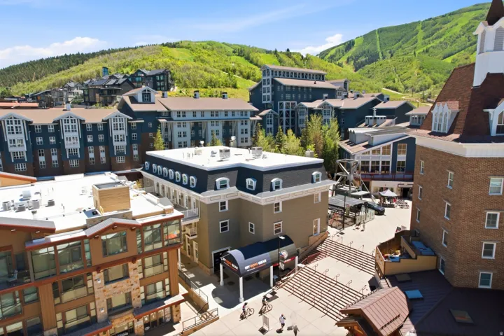 Mountain resort community featuring diverse architectural styles, visible pedestrian areas, and extensive surrounding treed hillsides